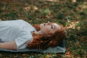 Femme pratiquant le yoga nidra en plein air par une journée ensoleillée, entourée par la nature.